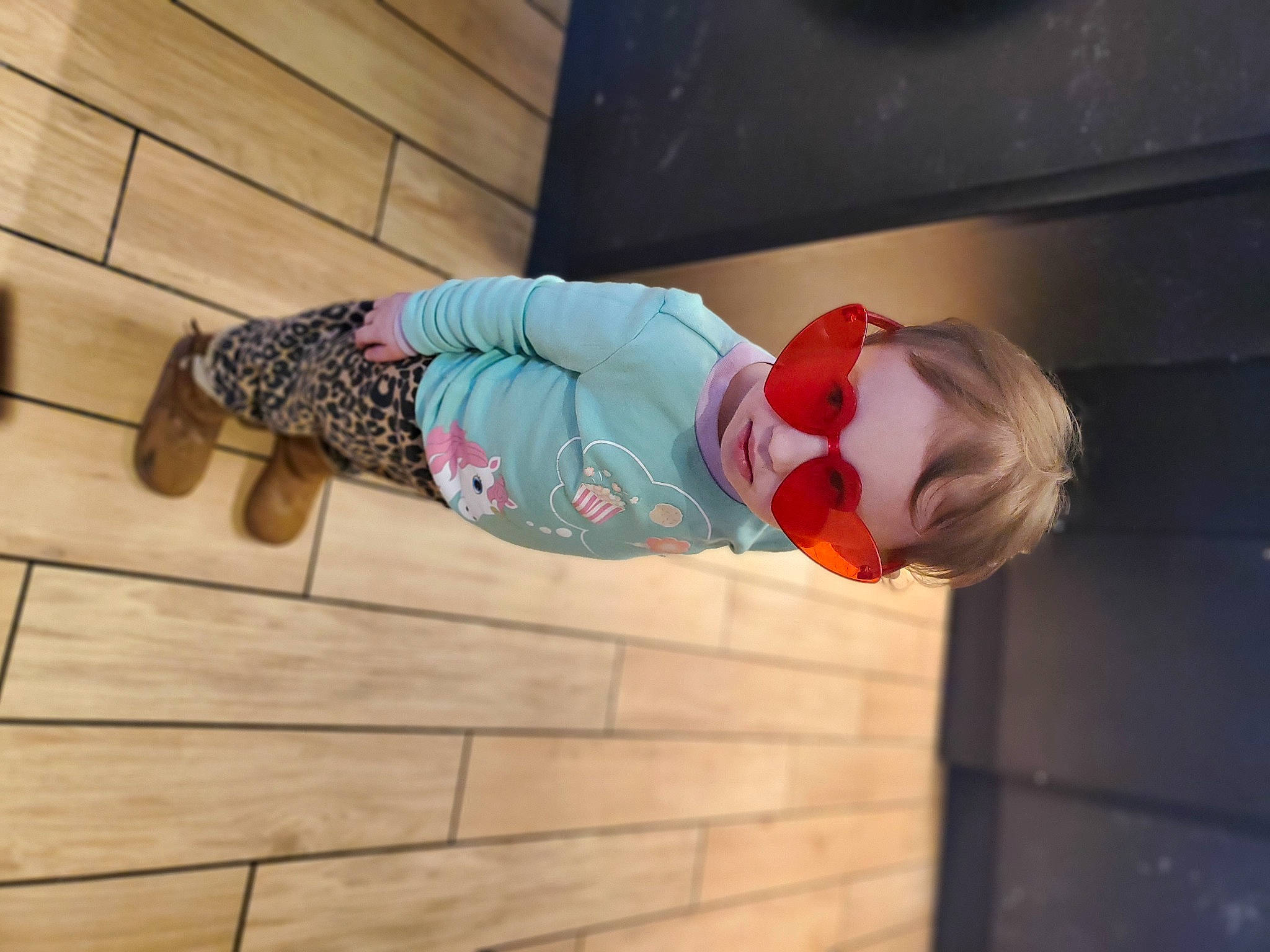 Jasmine Vallee is registered to the contest to win money with this photo: baby, baby_toddler_clothing, child, flooring, fun, goggles, hardwood, hat, leg, leisure, magenta, pattern, person, pink, room, smile, sunglasses, toddler, wood, wood_flooring