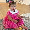 child, toddler, baby, portrait, sitting, indoors, pink_dress, polka_dots, flower_hair_clip, hairbrush, rug, carpet, wooden_floor, home, furniture, smiling, wide_eyed, barefoot, fashion, photography