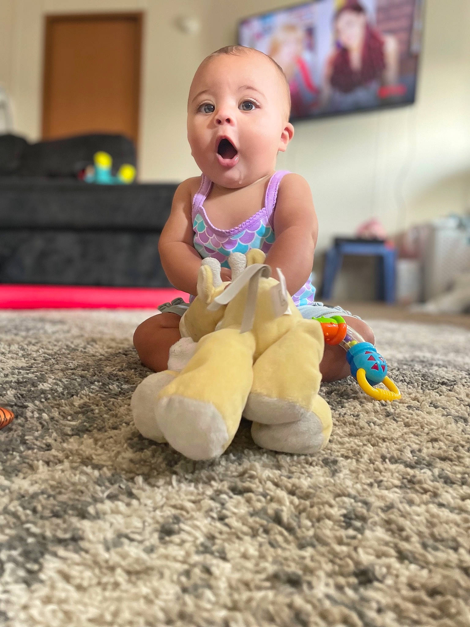 Patience is registered to the contest to win money with this photo: baby, baby_playing_with_toys, baby_toddler_clothing, baby_toys, blurred, child, comfort, face, floor, flooring, foot, fun, happy, human_leg, person, picture_frame, play, sitting, surprise, television