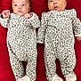 Parthi And Purvi is registered to the contest to win money with this photo: twin_babies, infant, baby, newborn, leopard_print, onesie, footed_pajamas, red_blanket, lying_down, portrait, cute, indoor, pair, sibling, sleepwear, face, hands, feet, soft_texture, cozy