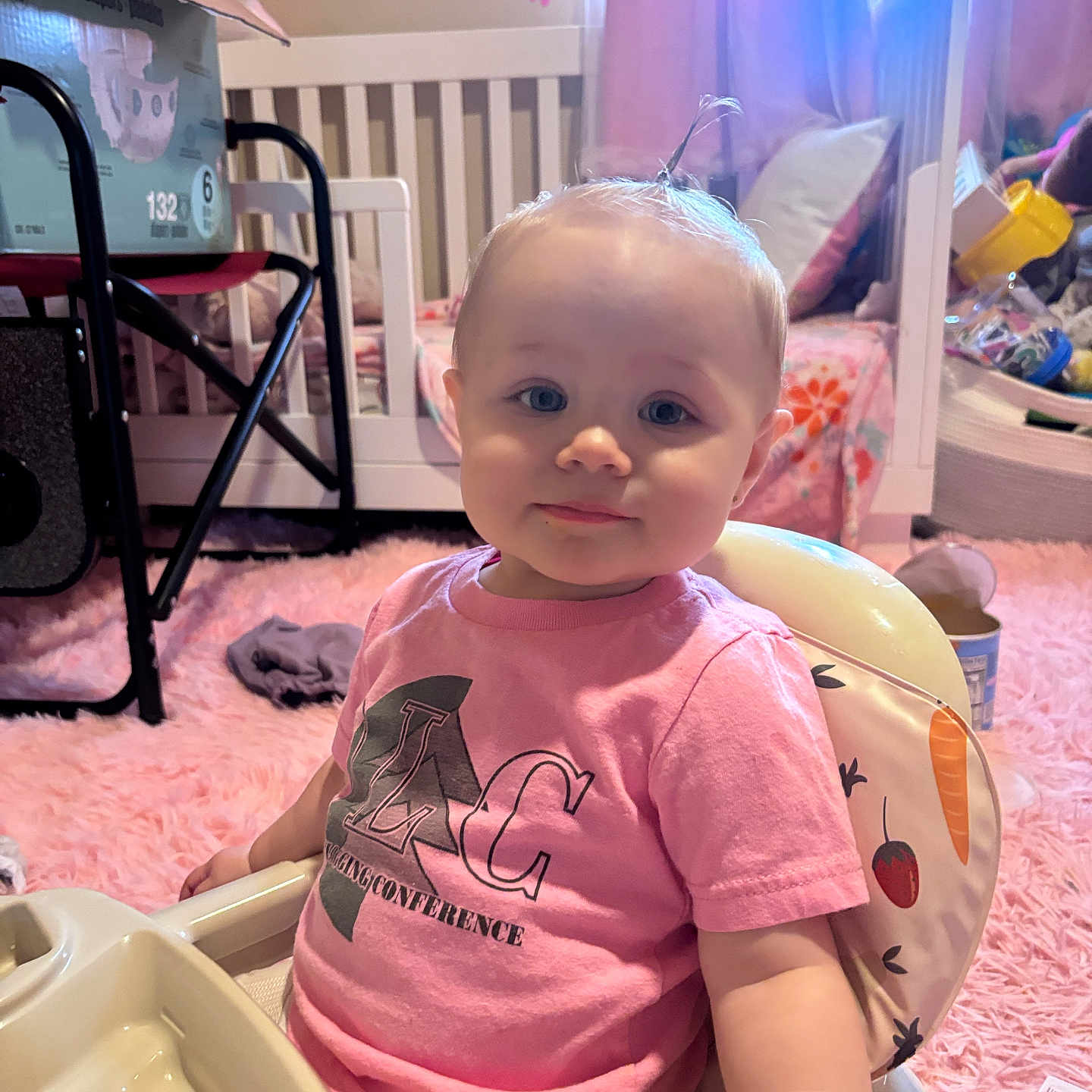 Raeah joined the competition — help win amazing prizes! baby, child, high_chair, pink_shirt, nursery, crib, carpet, toy, face, person, indoor, cute, hair, expression, seat, furniture, child_room, soft_lighting, smile, toddler