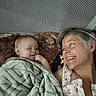baby, woman, smile, blanket, face, person, happy, indoor, bed, fabric, texture, blanket_pattern, skin, head, hair, portrait, candid, affection, family, love