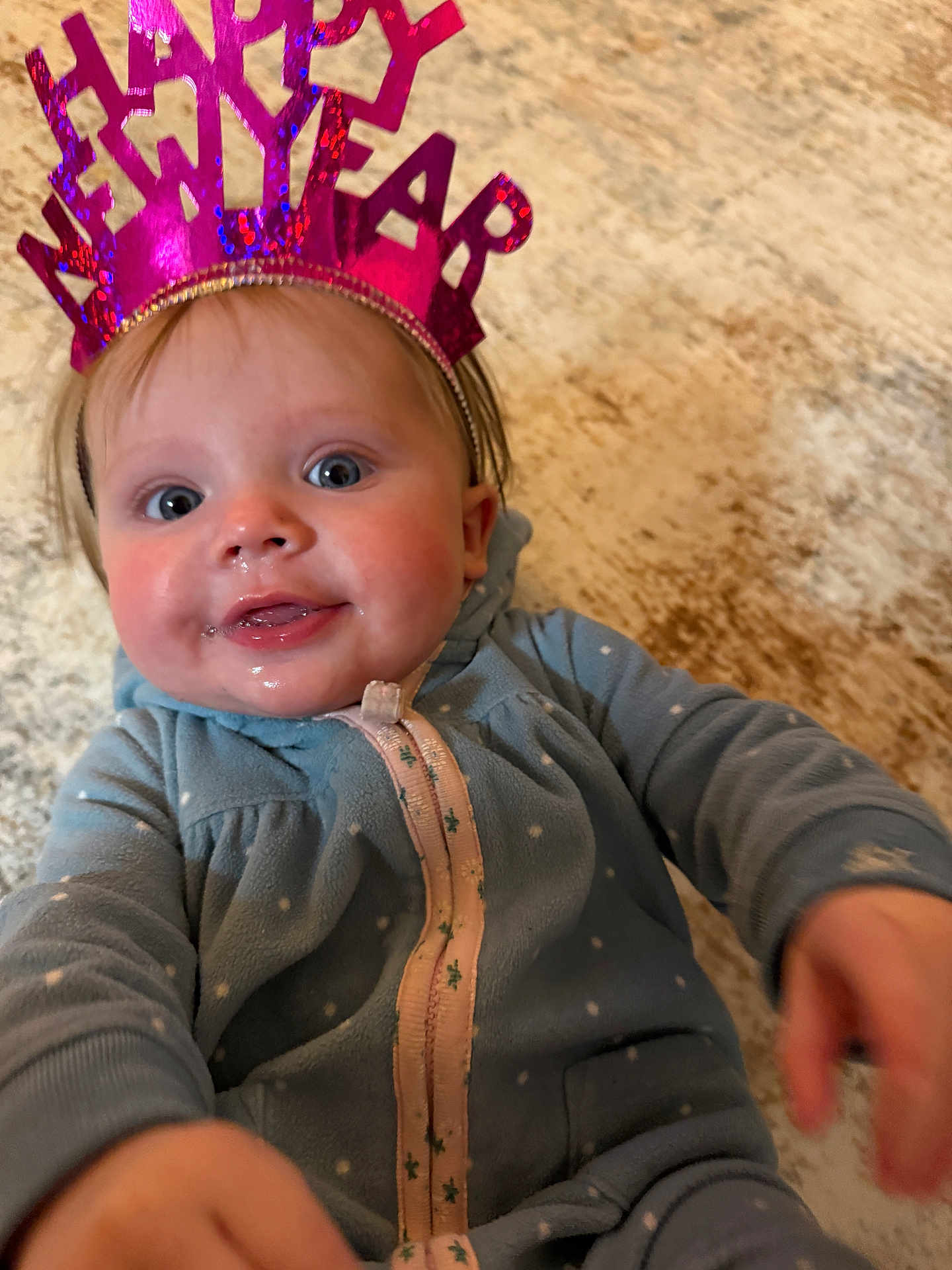 Mia is registered to the contest to win money with this photo: baby, child, new_year, headband, blue_onesie, polka_dots, face, happy, hands, carpet, indoor, smiling, cute, infant, portrait, closeup, expression, celebration, holiday, person