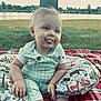 Weston joined the competition — help win amazing prizes! baby, child, outdoor, grass, lake, pillow, plaid_blanket, tongue_out, smile, cute, nature, trees, summer, sitting, clothing, person, infant, playful, daylight, cheeky
