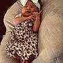 baby, sleeping, infant, headband, bow, leopard_print, dress, clothing, cushion, soft_texture, cozy, peaceful, cute, child, newborn, person, resting, skin, foot, hand