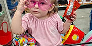 Anya joined the competition — help win amazing prizes! toddler, shopping_cart, pink_sunglasses, toy, snack, store_interior, autumn_decor, flowers, child, baby, retail, colorful, hair_bows, clothing, hand, face, person, sitting, plastic_toys, supermarket
