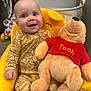 Grayson joined the competition — help win amazing prizes! baby, child, plush_toy, winnie_the_pooh, yellow_chair, pajamas, smiling, indoors, toy, stuffed_animal, face, hand, happy, seated, carpet, clothing, room, cute, childcare, portrait