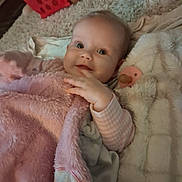 Alyra is registered to the contest to win money with this photo: baby, infant, child, portrait, face, eyes, smile, lying_down, blanket, pink_blanket, plush, pacifier, clothing, striped_sleeve, bed, cozy, indoors, close_up, soft_lighting, happy