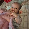 baby, infant, child, portrait, face, eyes, smile, lying_down, blanket, pink_blanket, plush, pacifier, clothing, striped_sleeve, bed, cozy, indoors, close_up, soft_lighting, happy