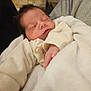 newborn, baby, sleeping, blanket, soft, wrapped, infant, peaceful, person, hand, clothing, grey_sleeve, stone_wall, indoor, portrait, cute, serene, closeup, resting, warm
