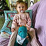 Mayllie a rejoint le concours — aidez-le/la à gagner de superbes lots ! toddler, pacifier, plush_toy, dinosaur, pajamas, couch, pillow, toys, christmas_tree, indoor, child, face, person, furniture, room, stacked_books, chair, green_wall, purple_blanket, happy_baby