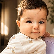 Arya is registered to the contest to win money with this photo: baby, child, infant, face, smile, eyes, hair, clothing, indoor, cushion, light, portrait, skin, cute, young, warm_light, soft_focus, person, cozy, expression