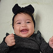 Gemma joined the competition — help win amazing prizes! baby, smiling, black_bow, black_clothing, cushion, happy, infant, child, headband, portrait, cute, indoors, person, fashion, sitting, young_child, face, hands, joy, expression