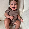 Gemma joined the competition — help win amazing prizes! baby, child, smiling, laughing, headband, bow, brown_clothing, sitting, couch, indoor, footwear, shoes, happy, cute, infant, portrait, person, furniture, soft_lighting, closeup