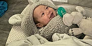 Micheal joined the competition — help win amazing prizes! baby, smiling, hoodie, plush_toy, elephant, blanket, pacifier, indoor, floor, toy_truck, wooden_floor, child, cute, warm_clothing, infant, happy, face, headwear, soft_texture, cozy