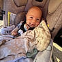 Parker is registered to the contest to win money with this photo: baby, blanket, car_seat, child, clothing, comfort, cozy, cute, fabric, face, head, indoors, infant, pacifier, rest, seatbelt, smile, soft, wrapped, young