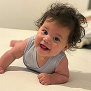 Paola participe au concours pour gagner de l'argent avec cette photo : baby, bed, child, curly_hair, cute, expression, eyes, face, hand, happy, indoor, infant, lying_down, person, portrait, skin, sleeveless_shirt, smiling, toddler, young