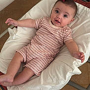 Laura participe au concours pour gagner de l'argent avec cette photo : baby, infant, child, striped_clothing, hair_clip, cushion, chair, indoor, floor, relaxed, smiling, cute, person, skin, short_sleeves, legs, arms, head, eyes, mouth