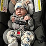 baby, sleeping, car_seat, pajamas, hat, infant, child, safety_harness, cute, soft_lighting, indoors, adorable, resting, toddler, clothing, fabric, comfort, seat, headwear, peaceful