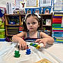 child, girl, toy, dice, classroom, education, play, pigtails, bows, table, colorful, learning, preschool, furniture, storage, shelf, plastic, cute, indoor, person