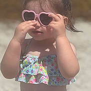 Taliah joined the competition — help win amazing prizes! child, toddler, sunglasses, heart_shaped, swimsuit, floral_pattern, beach, sunny, outdoor, summer, hair_tie, pink, playing, sunlight, cute, fashion, portrait, person, skin, hands