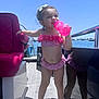Taliah is registered to the contest to win money with this photo: child, girl, bikini, pink, sippy_cup, boat, water, sky, reflection, sunny, outdoor, summer, vacation, deck, barefoot, hair_bow, happy, standing, toy, playful