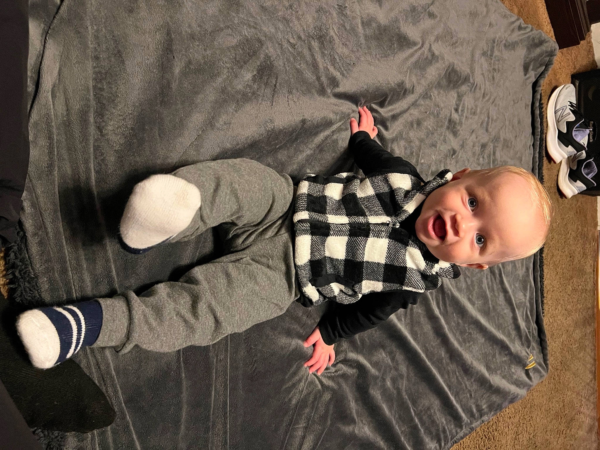 Makai is registered to the contest to win money with this photo: baby, baby_products, baby_toddler_clothing, child, comfort, elbow, fun, gesture, human_leg, linens, pattern, person, plaid, sitting, sleeve, sock, tartan, toddler, tree, wood