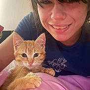 Nala is registered to the contest to win money with this photo: person, woman, cat, kitten, orange_cat, pet, cuddling, smiling, portrait, selfie, indoors, blue_shirt, pink_blanket, brown_hair, whiskers, ears, eyes, close_up, home, cute