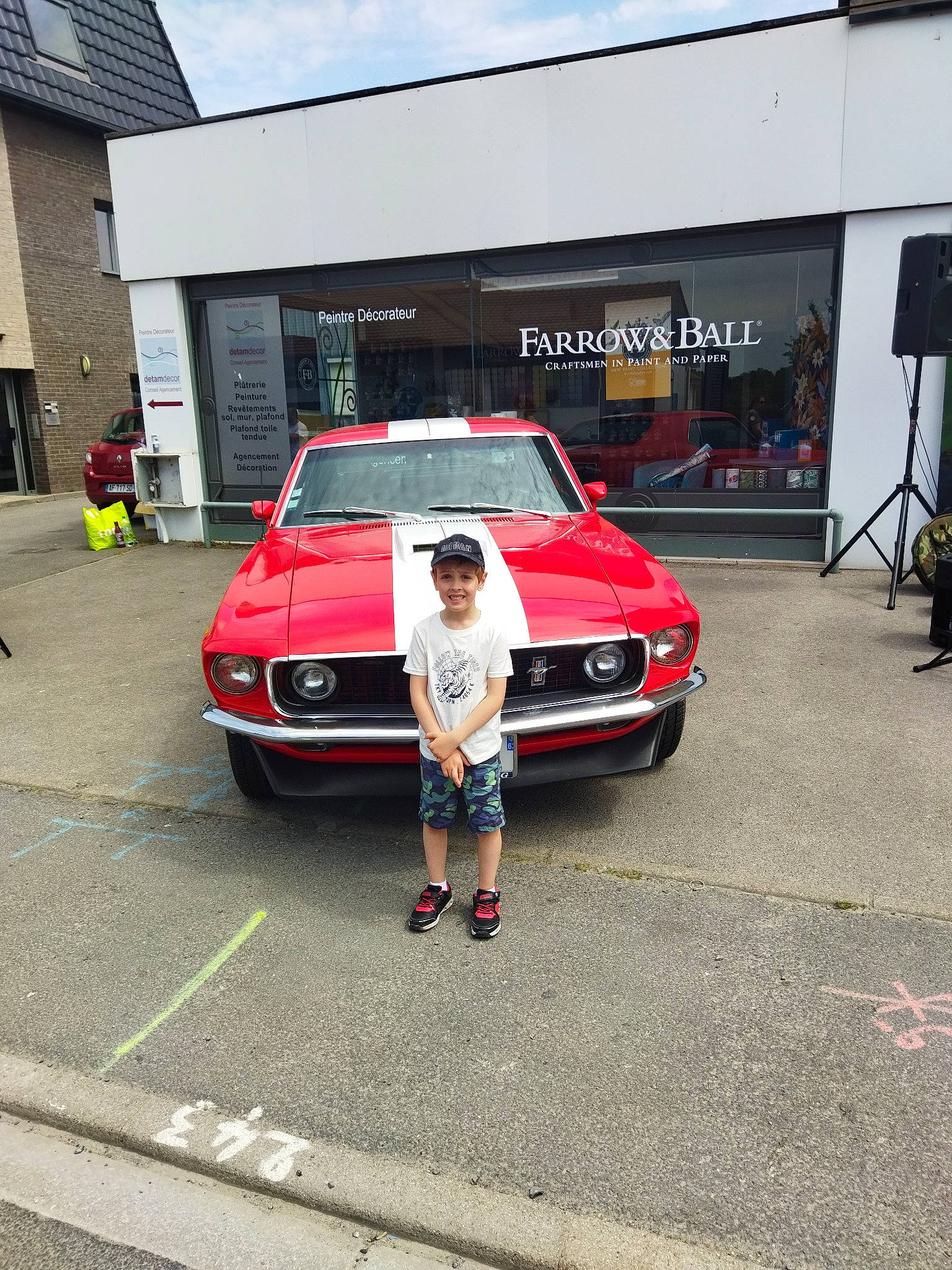 Nathéo participe au concours pour gagner de l'argent avec cette photo : asphalt, automotive_design, automotive_exterior, building, bumper, car, classic_car, family_car, full_size_car, headlamp, headwear, hood, joy, motor_vehicle, person, personal_luxury_car, shorts, sky, tire, vehicle