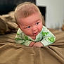 baby, bed, blanket, child, curious, cute, drool, expression, face, green_clothing, hands, head, indoors, infant, lying_down, onesie, portrait, skin, soft, young_child