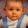 baby, child, blue_eyes, overalls, white_shirt, face, portrait, close_up, curious, cute, infant, young_child, skin, hair, clothing, studio, indoors, expression, person, small_hand