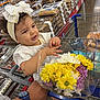 Amada is registered to the contest to win money with this photo: toddler, child, shopping_cart, flowers, bouquet, headband, bow, supermarket, aisle, baked_goods, hand, watch, clothing, white_dress, floor, package, food, retail, store, happy