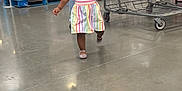 Kaylani is registered to the contest to win money with this photo: toddler, child, shopping_cart, store, aisle, dress, bows, shoes, floor, person, retail, shopping, happy, walking, colorful, clothing, shelves, product, indoor, grocery