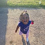 child, toddler, outdoor, sunlight, grass, sidewalk, happy, smiling, braids, beads, purple_shirt, pink_pants, white_sandals, toy, shadow, playful, person, daylight, concrete, casual_clothing