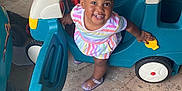 Kaylani joined the competition — help win amazing prizes! child, colorful_bows, cute, dress, floor, fun, garage, happy, indoor, person, plastic_toy, playroom, plaything, playtime, shoes, smiling, toddler, toy_car, vehicle, young_child