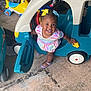 Kaylani joined the competition — help win amazing prizes! toddler, child, smiling, toy_car, playroom, colorful_bows, dress, shoes, indoor, floor, plastic_toy, vehicle, happy, cute, person, playtime, garage, plaything, young_child, fun