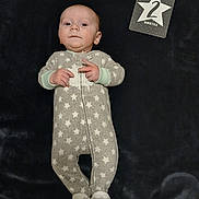 Ryder is registered to the contest to win money with this photo: baby, baby_clothes, blanket, card, cute, expression, fabric, face, feet, indoor, infant, lying_down, milestone_card, newborn, onesie, portrait, slippers, soft_lighting, star_pattern, two_months