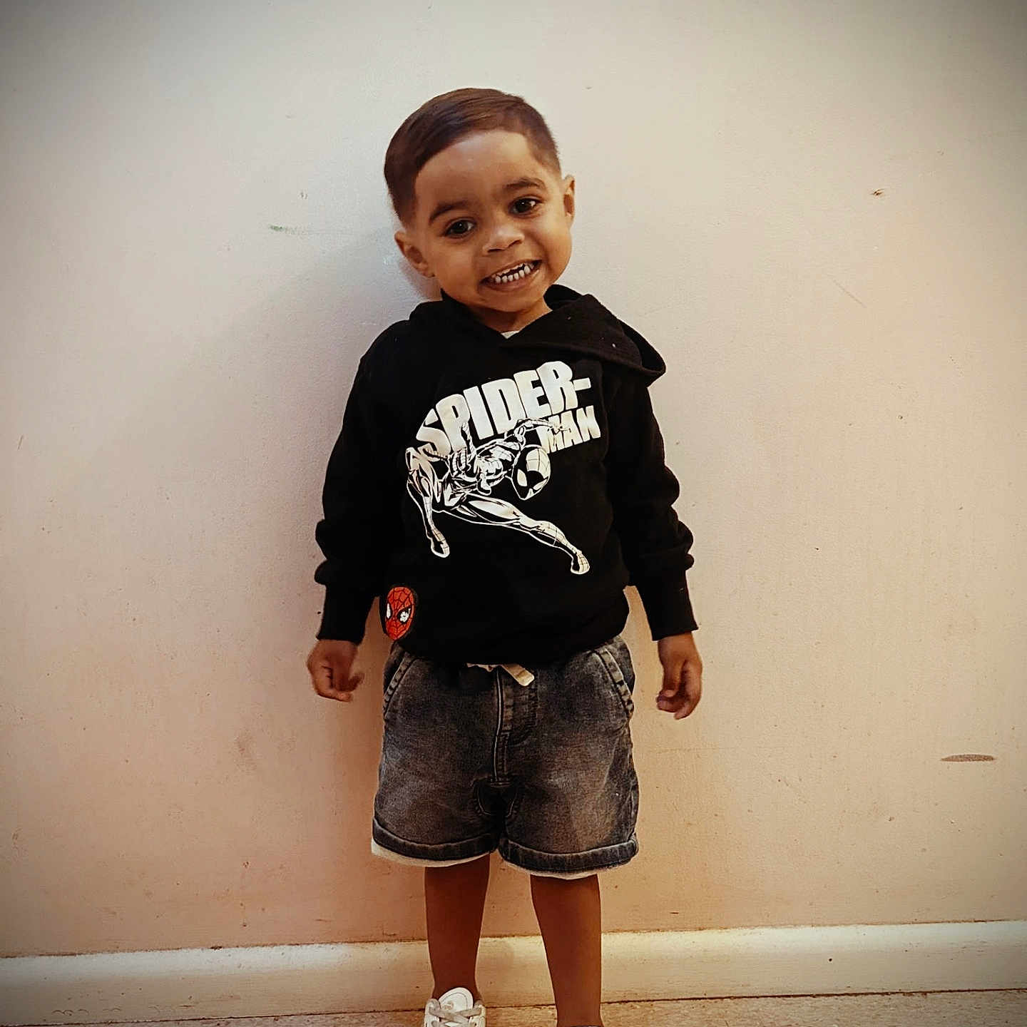 Lahkeil is registered to the contest to win money with this photo: boy, casual_clothing, child, cute, denim_shorts, fashion, feet, floor, happy, hoodie, indoor, person, playful, portrait, smile, spiderman, standing, wall, white_sneakers, young