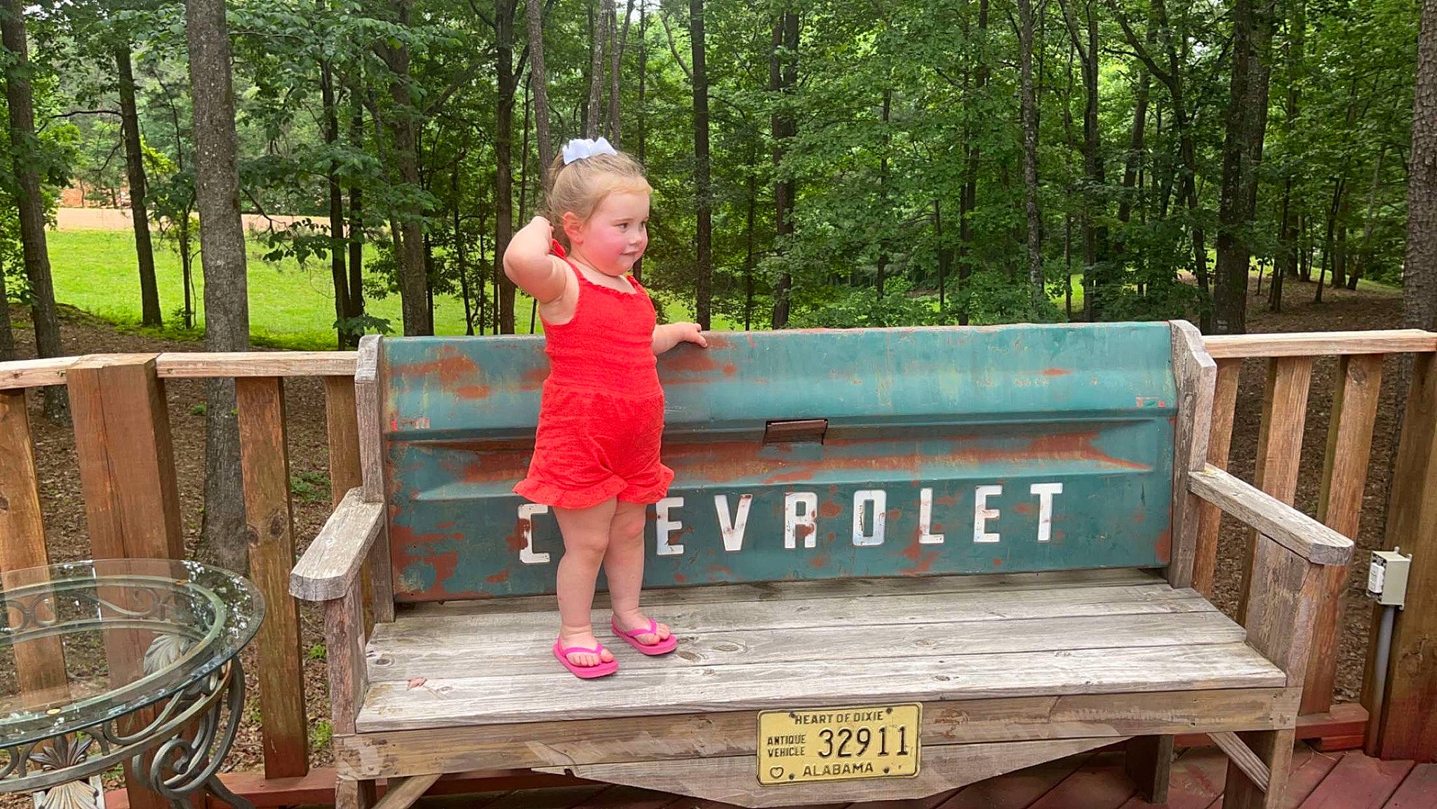 Della is registered to the contest to win money with this photo: child, fence, fun, garden, grass, leaf, leisure, nature, outdoor_bench, outdoor_furniture, person, plant, recreation, shorts, sitting, summer, table, toddler, tree, wood