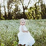 child, girl, white_dress, meadow, wildflowers, nature, outdoor, sunlight, trees, smile, happy, toddler, grass, summer, portrait, playful, flower_field, greenery, childhood, sunny