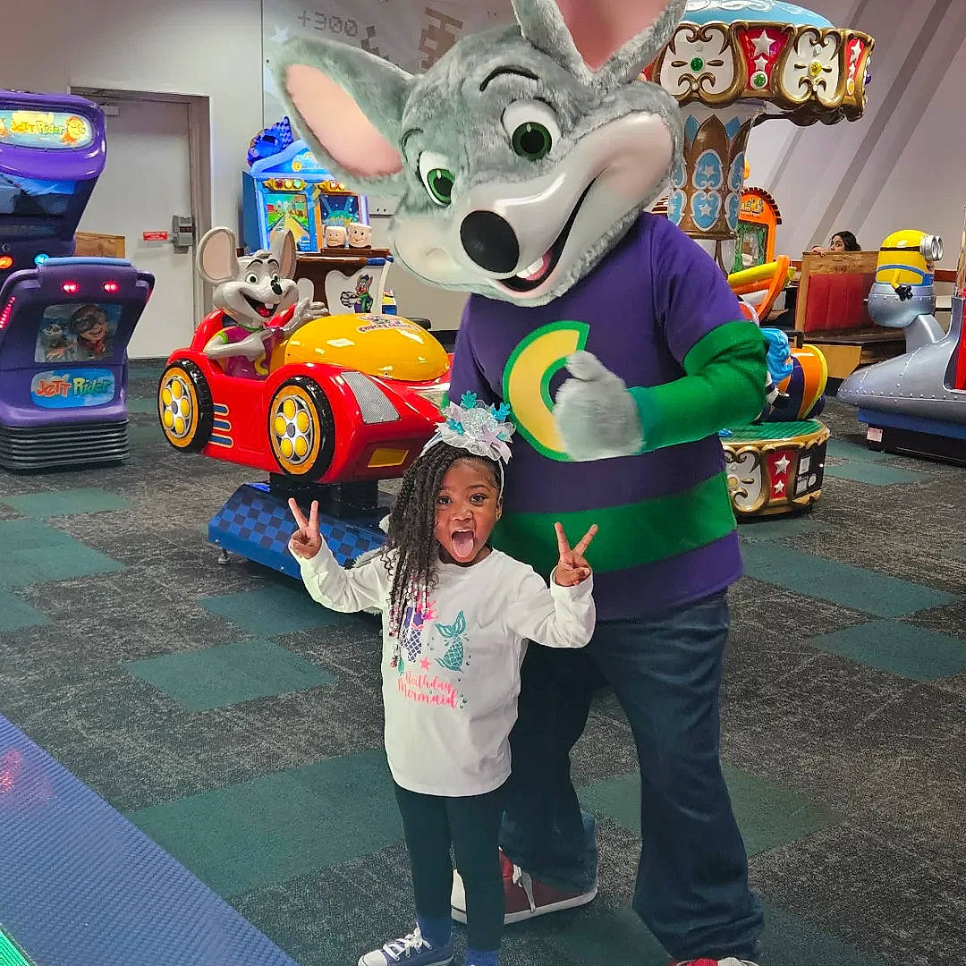 Nigé is registered to the contest to win money with this photo: child, costume, event, fictional_character, fun, games, happy, hat, leisure, mascot, motor_vehicle, person, photograph, play, recreation, smile, snapshot, t_shirt, tire, toddler