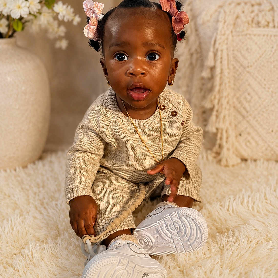 Genesis joined the competition — help win amazing prizes! toddler, child, baby, sitting, curious, knitwear, hair_bows, white_shoes, carpet, indoor, toy, beads, earrings, necklace, flowers, vase, decor, neutral_colors, portrait, cute