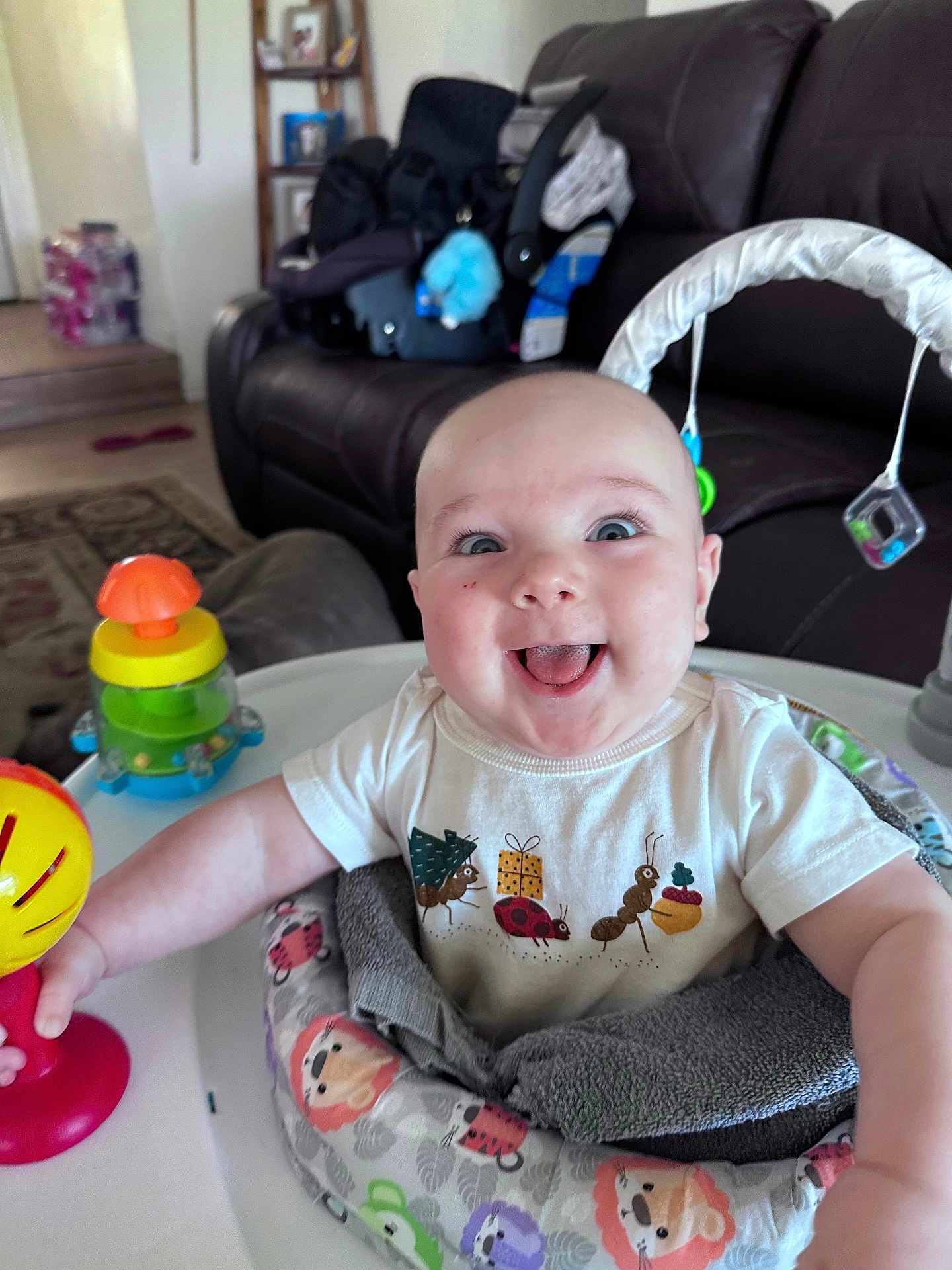 Gunner is registered to the contest to win money with this photo: baby, smiling, toy, baby_seat, indoor, living_room, couch, child, happy, person, clothing, toddler, furniture, play, infant, colorful, face, expression, home, seat