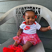 Séyori is registered to the contest to win money with this photo: baby, child, smile, happy, sitting, chair, plastic_chair, red_socks, frilly_skirt, nike_shirt, hair_accessories, cute, portrait, outdoor, wall, fashion, toddler, person, feet, clothing