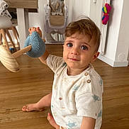 Nolan a rejoint le concours — aidez-le/la à gagner de superbes lots ! child, toddler, toy, wooden_floor, indoor, high_chair, curious, sitting, clothing, shorts, shirt, wood, furniture, baby, person, floor, home, cute, play, expression