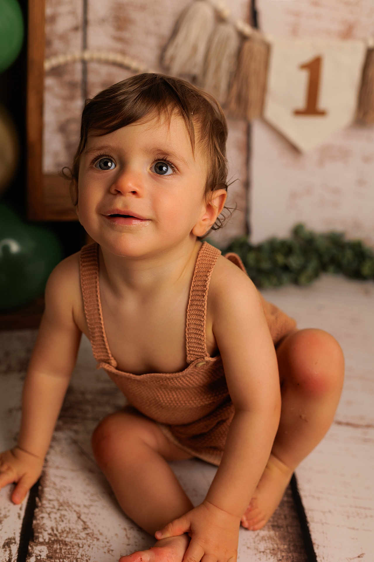 Nolan participe au concours pour gagner de l'argent avec cette photo : toddler, child, baby, blue_eyes, brown_hair, knitted_clothing, romper, sitting, floor, birthday, decorations, balloons, banner, celebration, portrait, cute, indoors, soft_lighting, expression, closeup