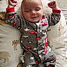William is registered to the contest to win money with this photo: baby, infant, sleeping, smiling, portrait, child, onesie, pajamas, train_pattern, blanket, cozy, indoor, lying_down, raised_arms, fists, pacifier, soft_lighting, bed, cute, relaxed