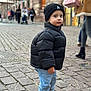Aaron participe au concours pour gagner de l'argent avec cette photo : child, toddler, black_jacket, beanie, street, cobblestone, urban, pedestrians, walking, building, window, shoes, jeans, cold_weather, winter_clothing, outdoor, curious, young, fashion, portrait