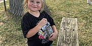 Davina joined the competition — help win amazing prizes! child, girl, smile, blonde_hair, black_shirt, denim_shorts, sneakers, outdoor, tree, bench, grass, sidewalk, bottle, daylight, people, park, casual_clothing, happy, person, nature