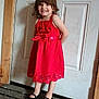 Delilah is registered to the contest to win money with this photo: child, girl, red_dress, smile, standing, door, door_handle, carpet, indoor, wood_floor, black_shoes, curtain, happy, person, home, young_child, floor_mat, hair, portrait, wall